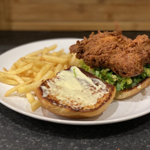 A plate with a KFC style burger with fries