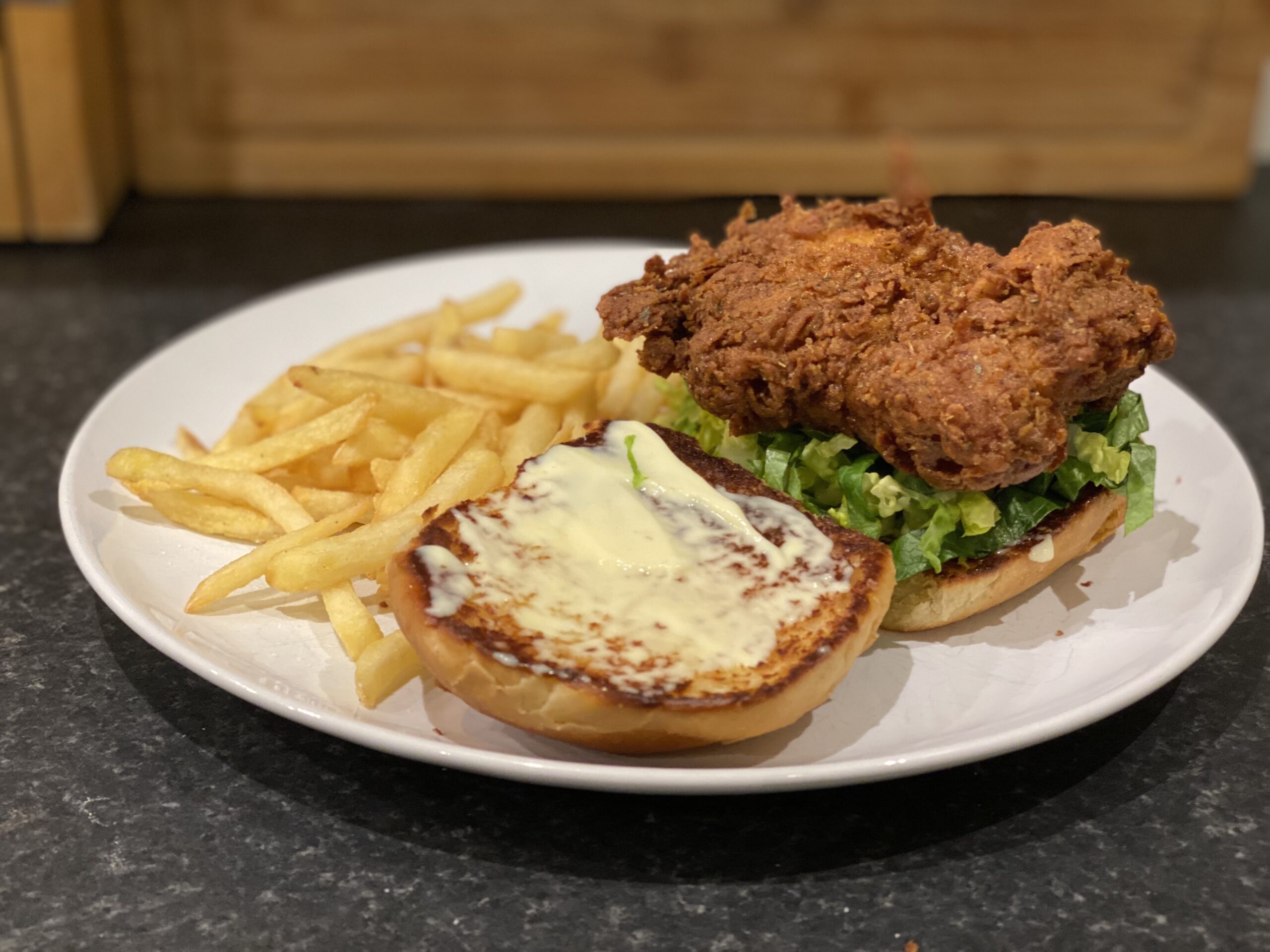 A plate with a KFC style burger with fries