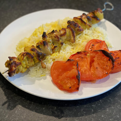 Chicken kebab on a bed of saffron rice and grilled tomato slices