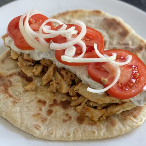 Chicken gyros with onion, tomato and tzatziki on a plate