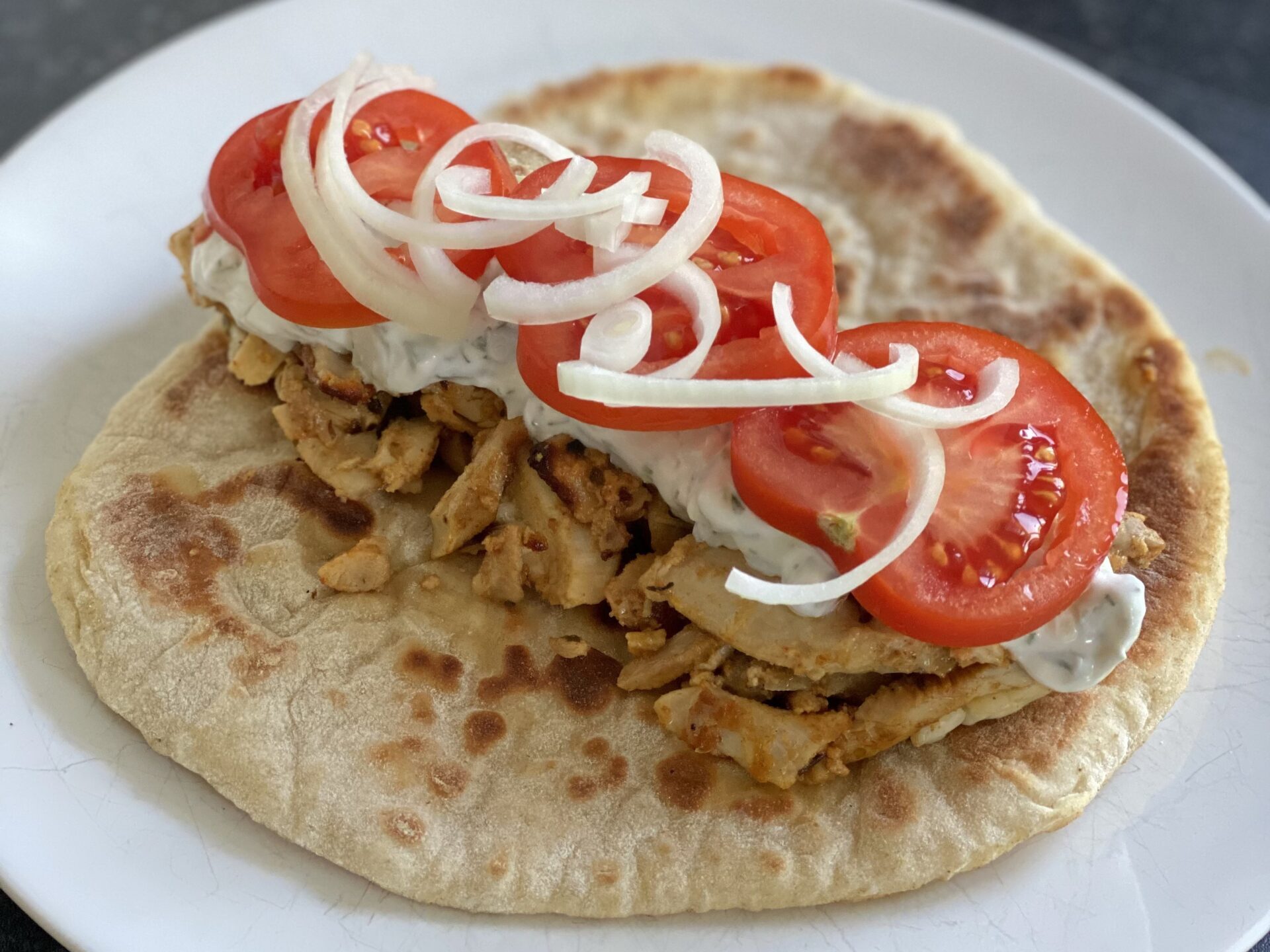 Chicken gyros with onion, tomato and tzatziki on a plate