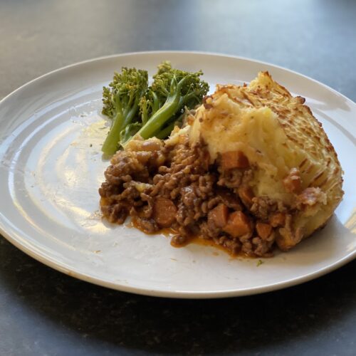 Shepherd's pie on a plate with some broccoli