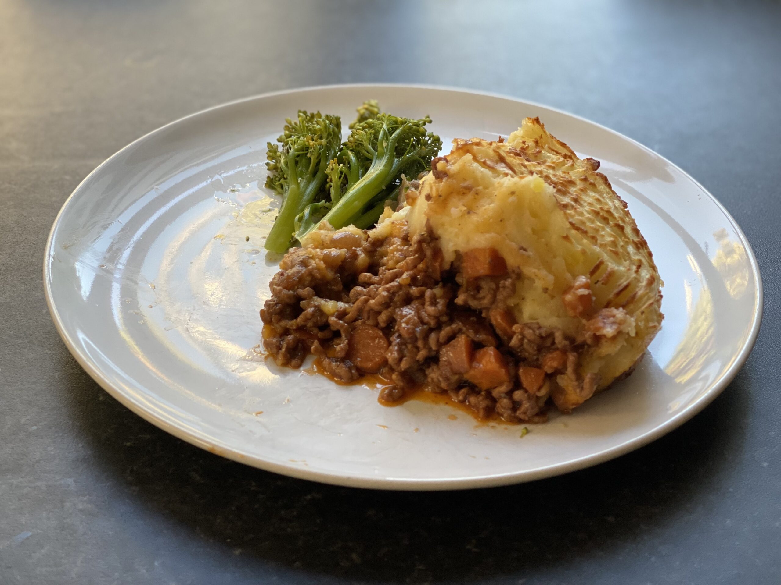 Shepherd's pie on a plate with some broccoli