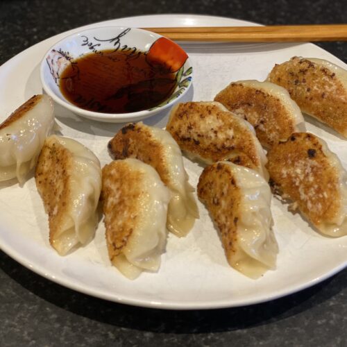 Plate with dumplings, chopsticks and some dipping sauce