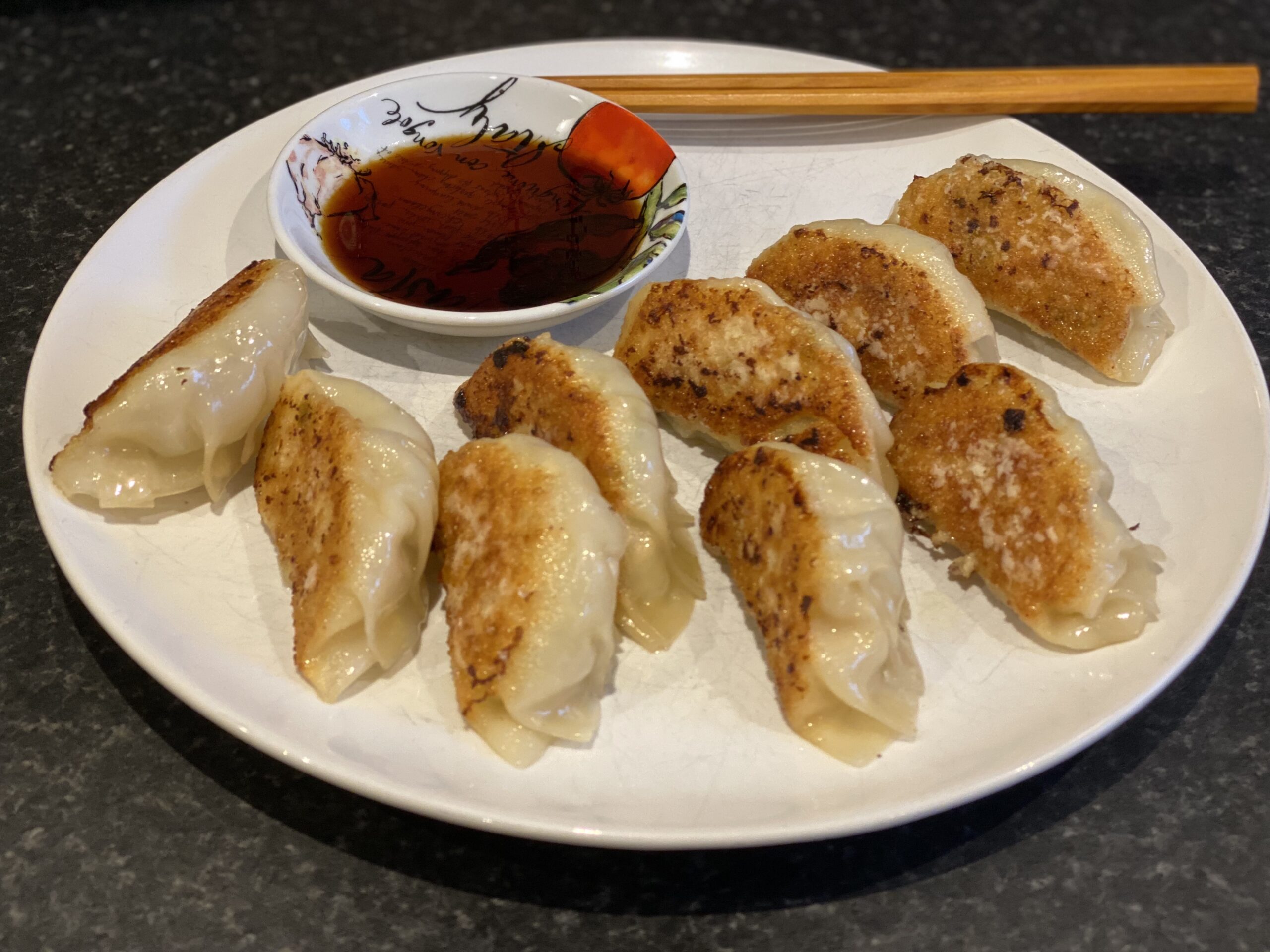 Plate with dumplings, chopsticks and some dipping sauce